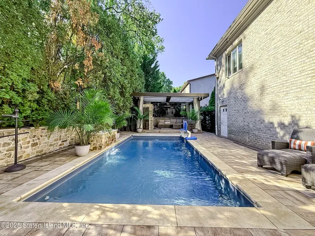 a view of a patio with table and chairs under an umbrella with a barbeque