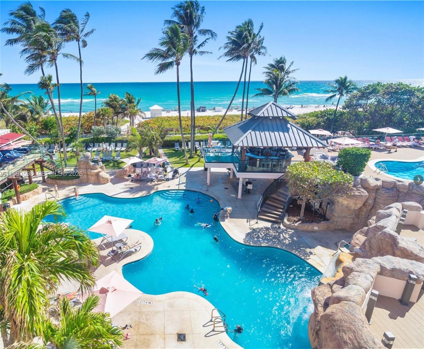 5225 Collins Avenue, Unit 1411 Miami Beach, FL 33140 - Photo 31 of 36 a view of a swimming pool with a table and chairs