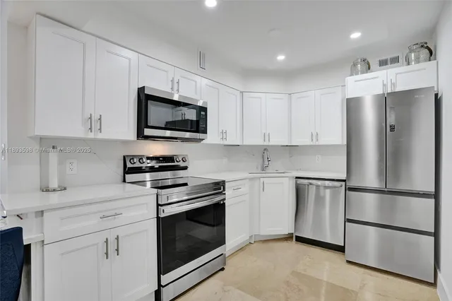 a large kitchen with granite countertop a stove a sink dishwasher a dining table and chairs with wooden floor