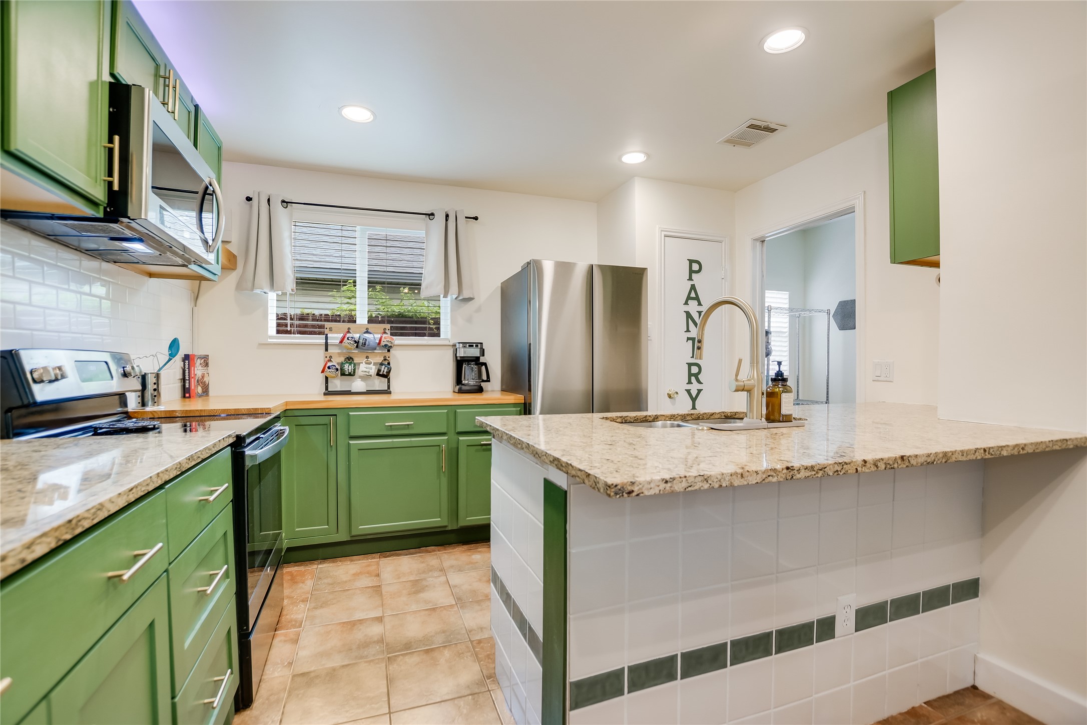 4702 Crest Oak Road Austin, TX 78744 - Photo 7 of 20 Kitchen featuring green cabinetry, stainless steel appliances, granite countertops, and a subway tile backsplash