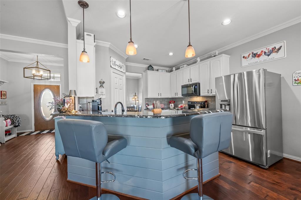 11277 Emerald Ranch Lane Forney, TX 75126 - Photo 7 of 32 a kitchen with stainless steel appliances granite countertop a refrigerator a sink dishwasher a dining table and chairs with wooden floor