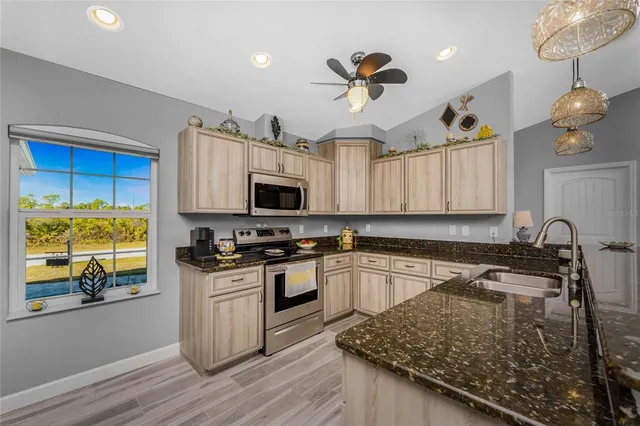 a kitchen with granite countertop a stove sink and microwave