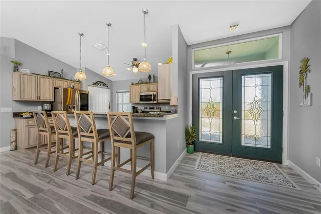 a kitchen with stainless steel appliances kitchen island granite countertop a table chairs and a chandelier