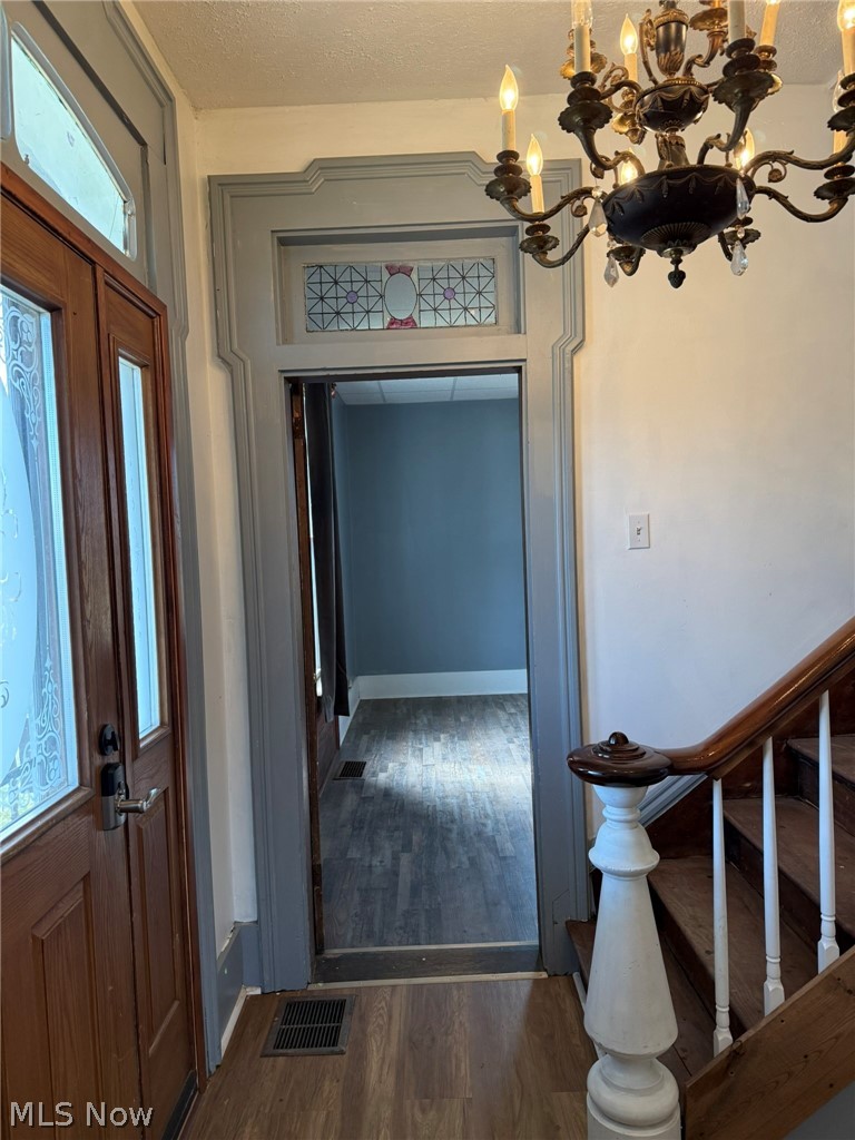 23033 Cadiz Road Freeport, OH 43973 - Photo 16 of 31 Entryway featuring suspended lighting, dark wood-style flooring, and a textured ceiling