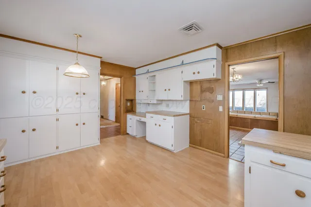 a kitchen with white cabinets and wooden floors