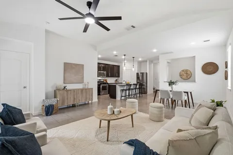 a living room with furniture kitchen view and a chandelier