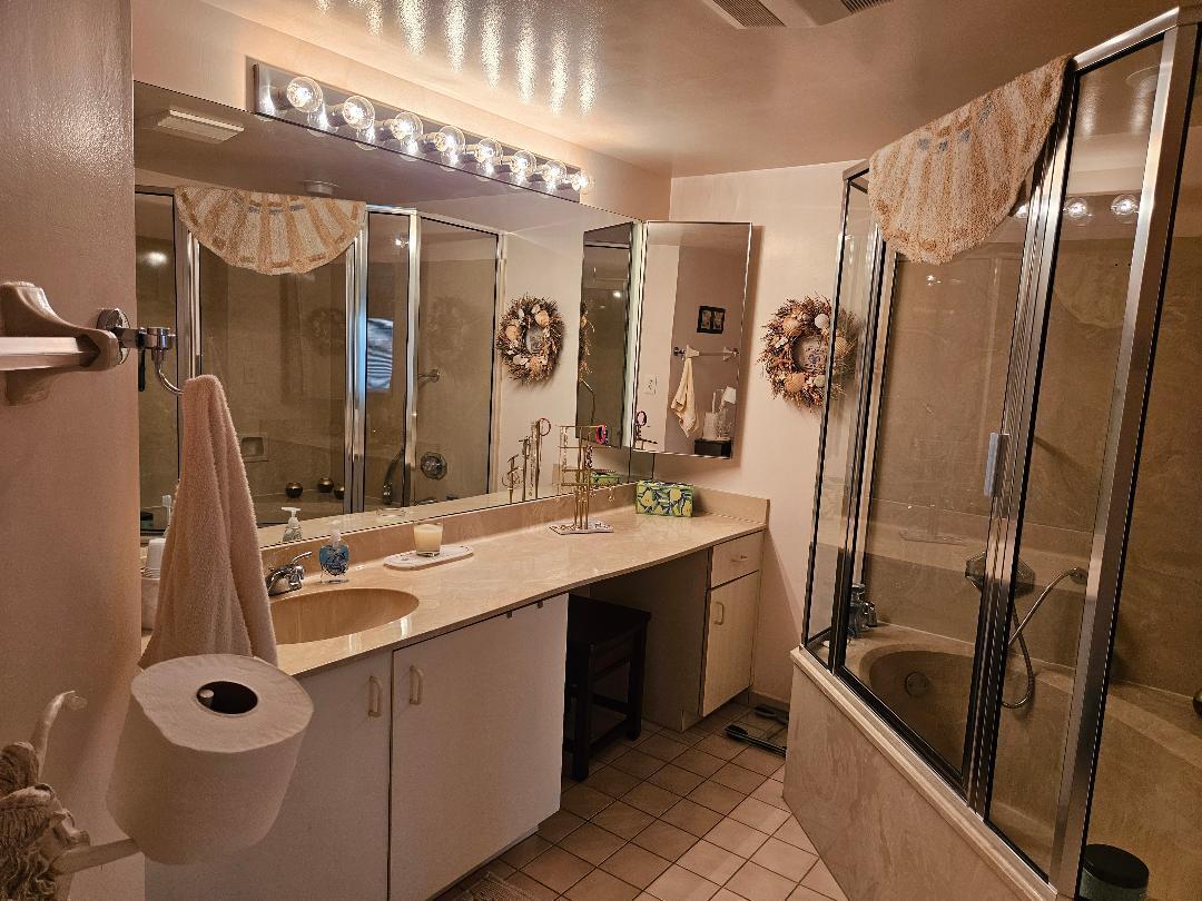 6070 Southeast Martinique Drive, Unit 103 Stuart, FL 34997 - Photo 16 of 30 a bathroom with a double vanity sink a mirror a bathtub and shower