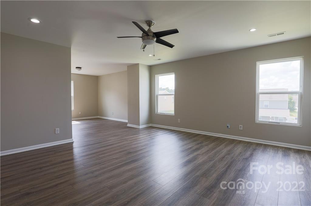 12507 Bending Branch Road Charlotte, NC 28227 - Photo 3 of 23 an empty room with wooden floor a ceiling fan and windows