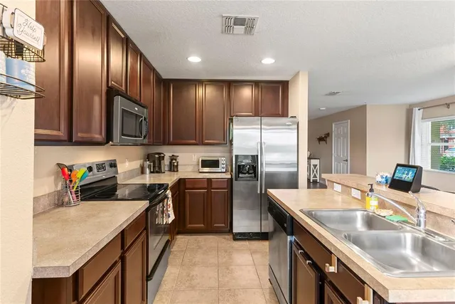 a kitchen with stainless steel appliances granite countertop a sink stove refrigerator and cabinets