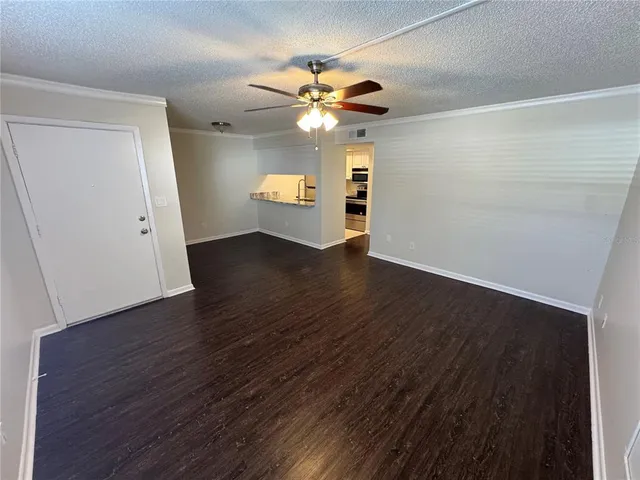 an empty room with wooden floor ceiling fan and window