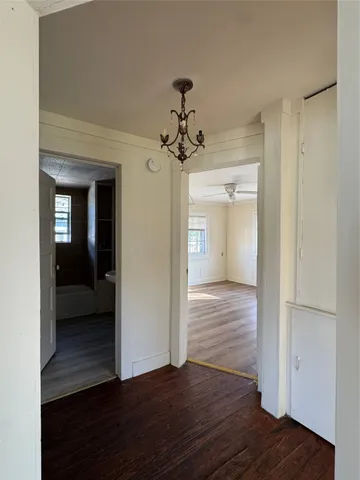 a view of a hallway with wooden floor and a living room
