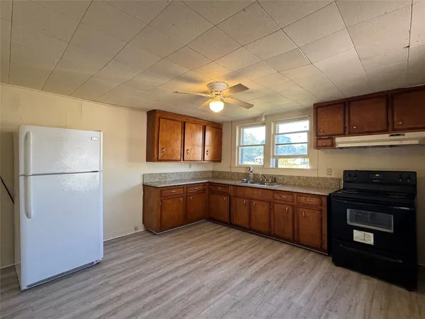 a kitchen with stainless steel appliances granite countertop a refrigerator a sink dishwasher a stove with wooden cabinets and floor