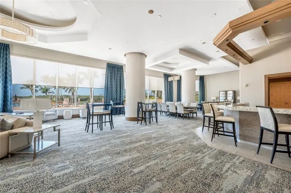 a room with lots of tables a large window and chairs