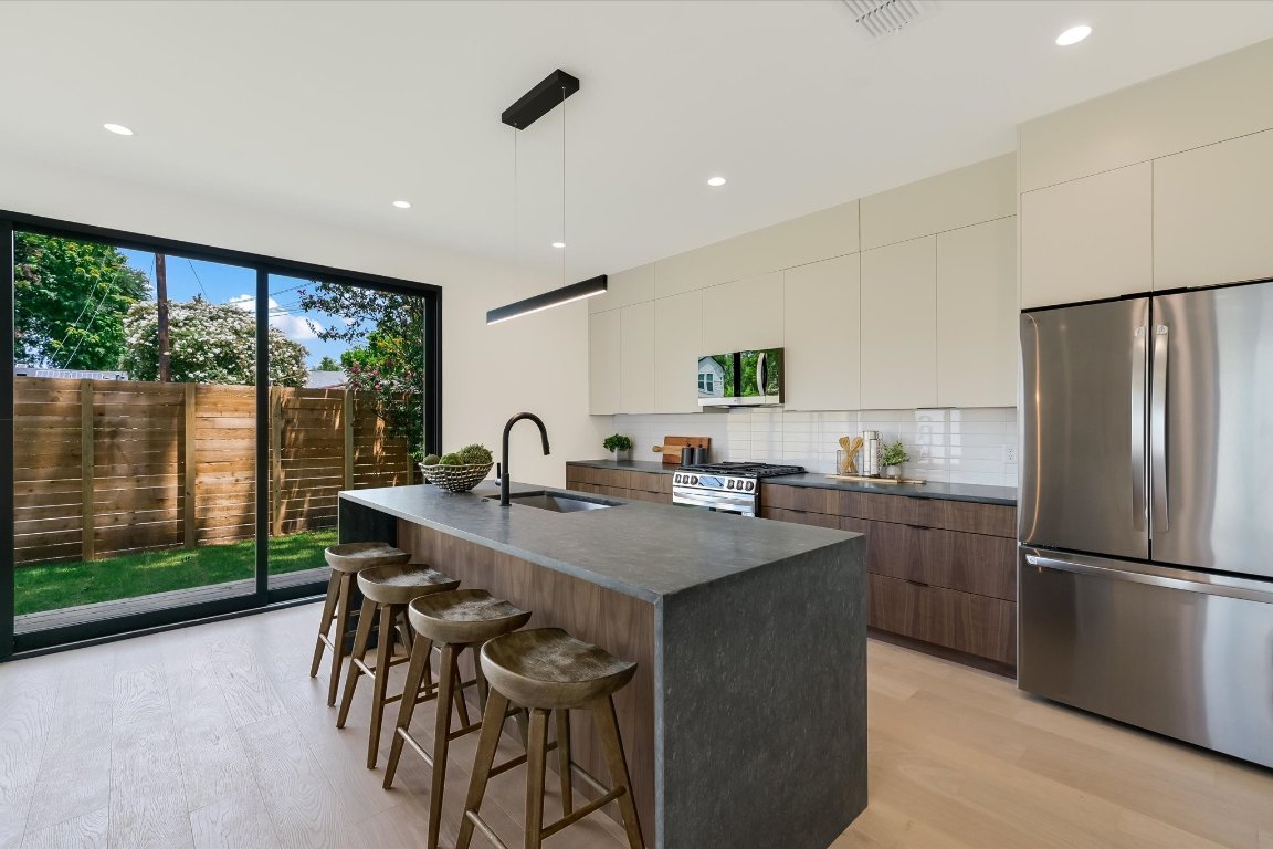 2705 Francisco Street, Unit A Austin, TX 78702 - Photo 2 of 21 Kitchen with appliances with stainless steel finishes, modern cabinets, dark countertops, a kitchen breakfast bar, and light wood-style flooring
