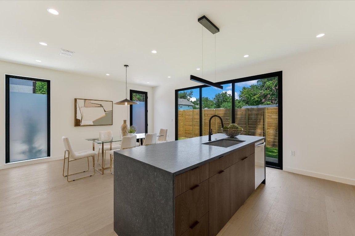 2705 Francisco Street, Unit A Austin, TX 78702 - Photo 7 of 21 Kitchen with modern cabinets, light wood-style floors, a large island with sink, recessed lighting, and dark countertops