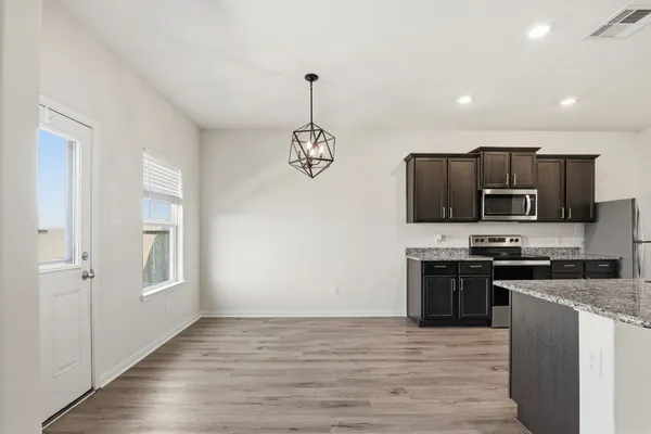 a kitchen with stainless steel appliances granite countertop a sink a stove top oven and wooden floor