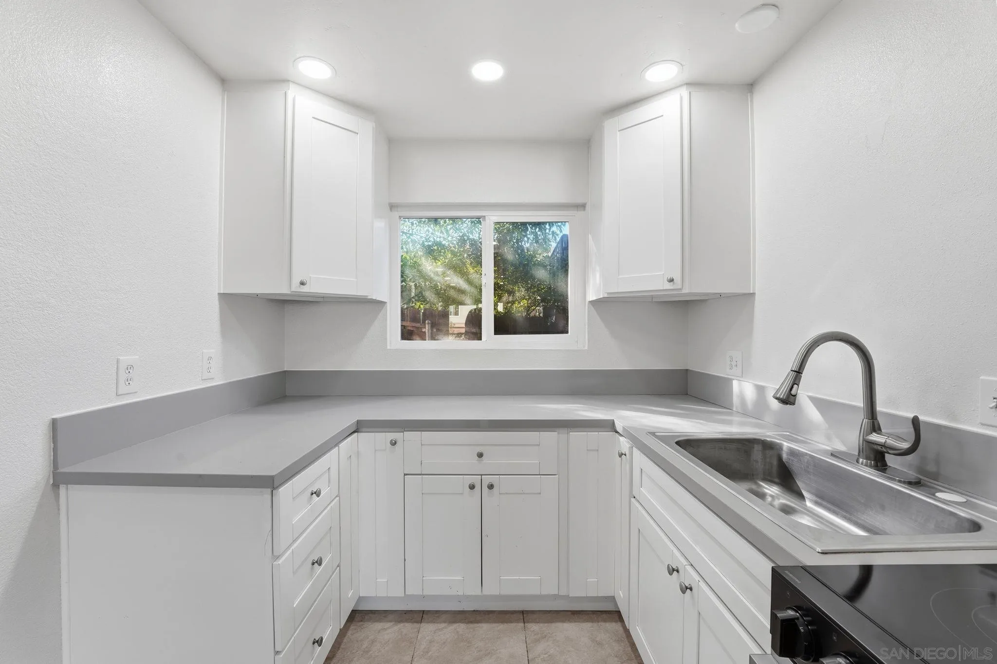 12621 Lindo Lane Lakeside, CA 92040 - Photo 21 of 28 a kitchen with white cabinets appliances a sink and a window