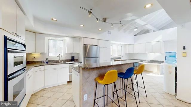 a kitchen with stainless steel appliances granite countertop a stove top oven a refrigerator a sink dishwasher a dining table and chairs with wooden floor