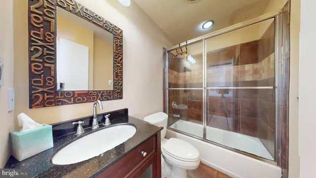 a bathroom with a granite countertop sink toilet a mirror and shower