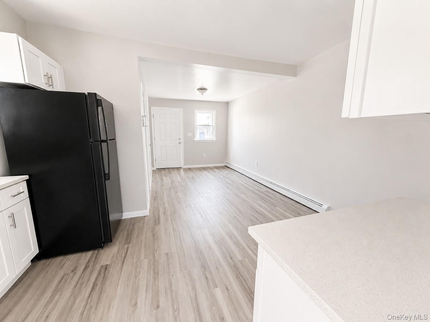 25 Monroe Street, Unit 1 Mount Vernon, NY 10550 - Photo 5 of 11 Kitchen area featuring white cabinetry, light-toned countertops, a black refrigerator, and wood-finish flooring