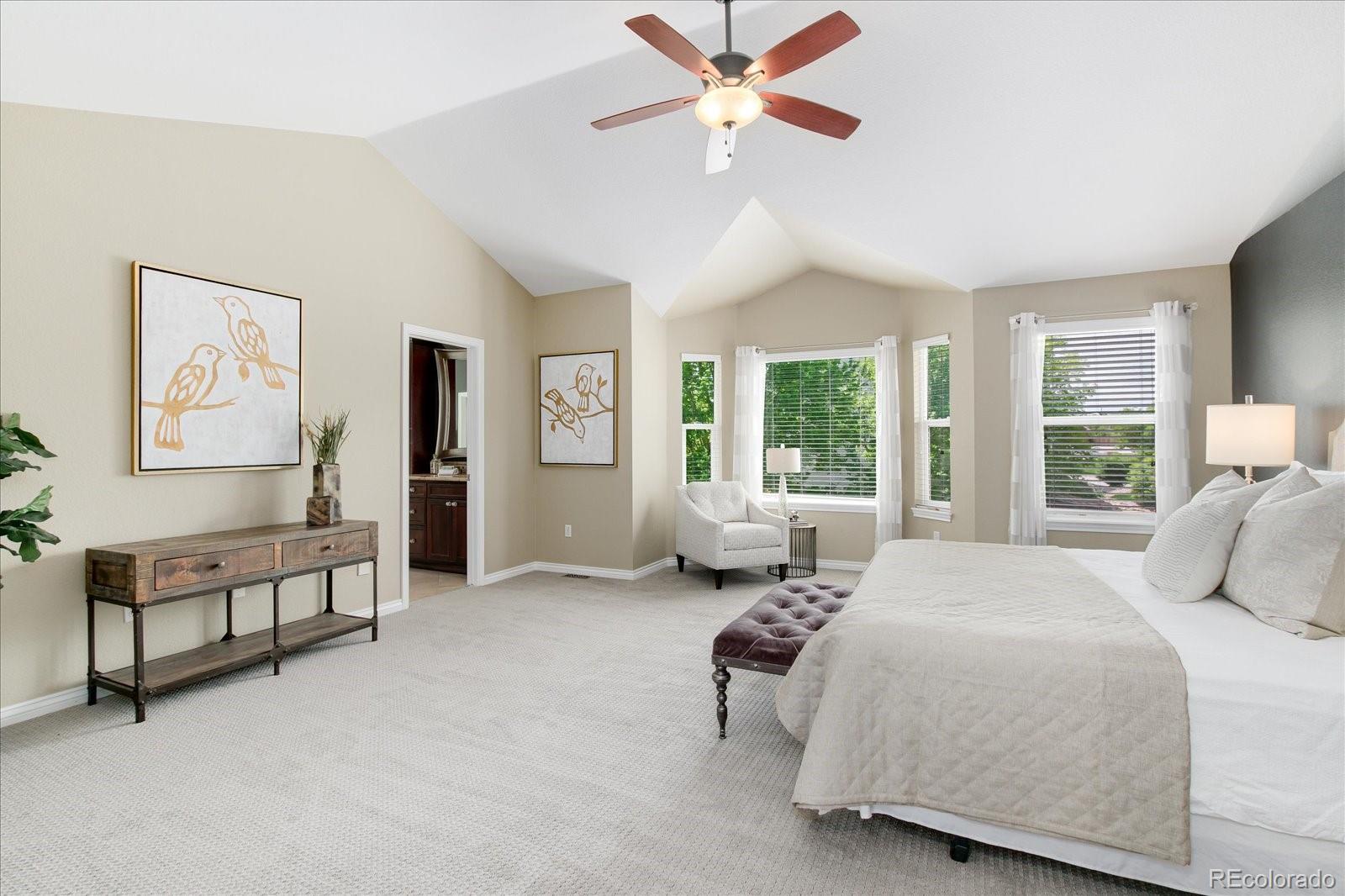 9318 Reed Way Broomfield, CO 80021 - Photo 17 of 33 a spacious bedroom with a bed a couch and a chandelier