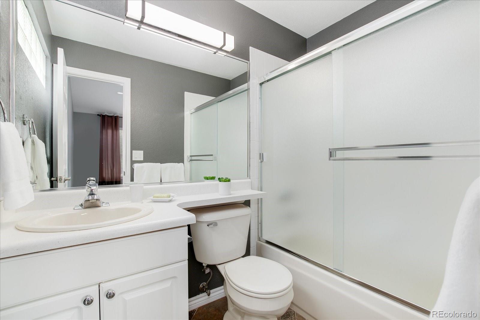 9318 Reed Way Broomfield, CO 80021 - Photo 24 of 33 a bathroom with a toilet sink vanity and mirror
