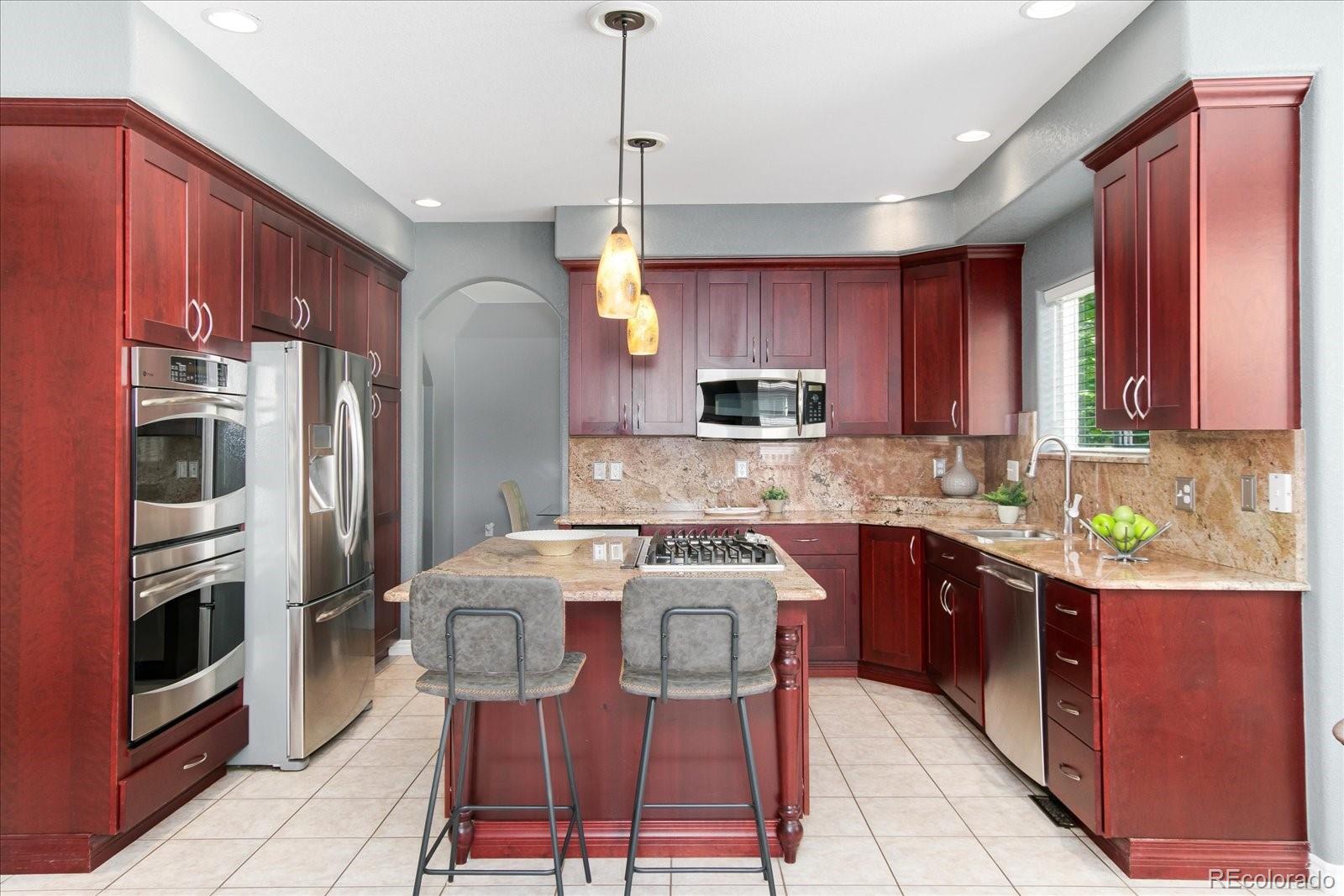 9318 Reed Way Broomfield, CO 80021 - Photo 8 of 33 a kitchen with stainless steel appliances granite countertop a refrigerator a stove a sink a dining table and chairs