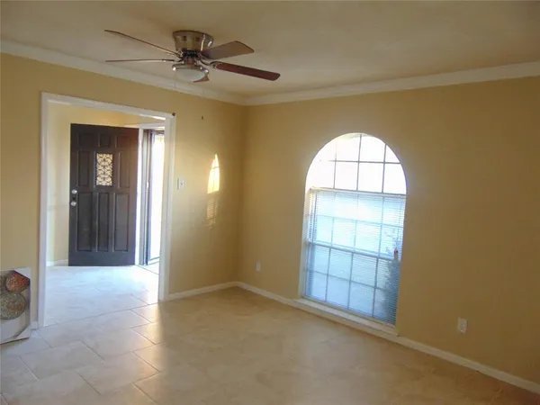 an empty room with chandelier fan and windows