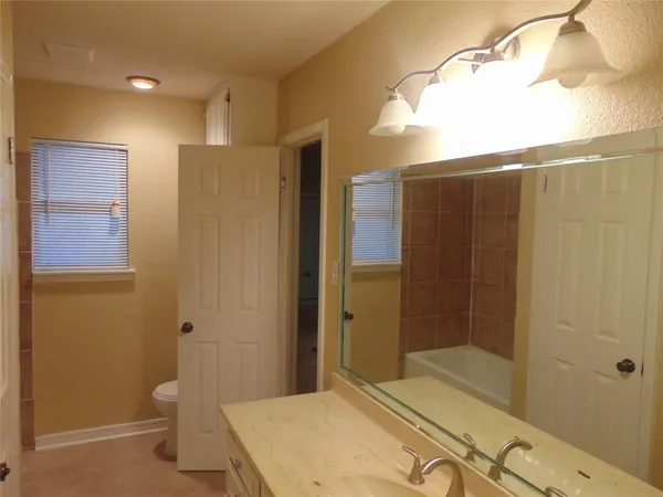 a bathroom with a granite countertop sink a toilet and shower