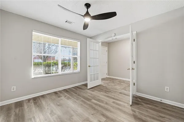 a view of an empty room with wooden floor and a window
