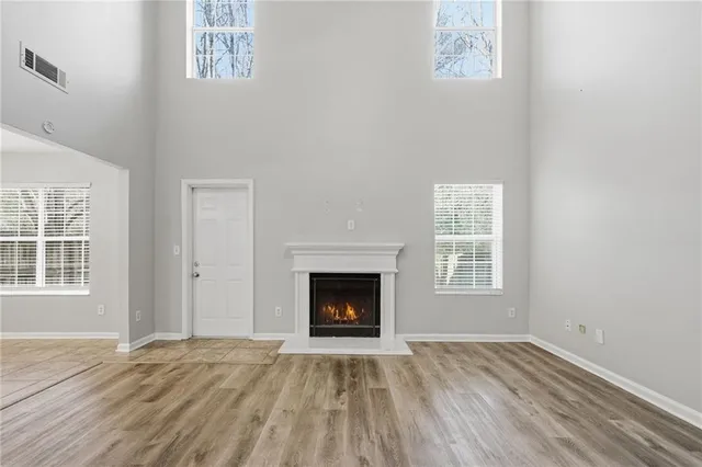 an empty room with wooden floor fireplace and windows
