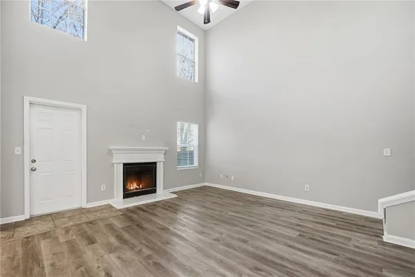 a view of an empty room with wooden floor fireplace and a window
