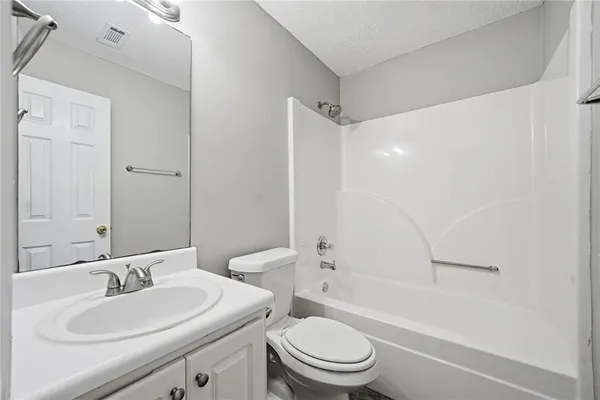 a bathroom with a toilet a sink a mirror a bathtub and vanity