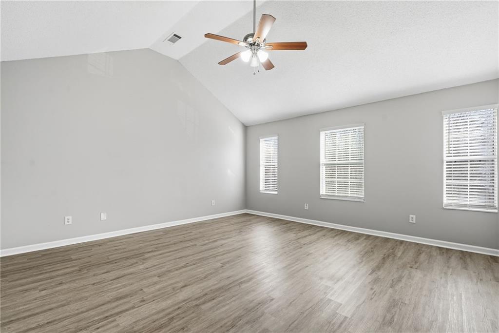 2297 Charleston Pointe Southeast Atlanta, GA 30316 - Photo 26 of 48 an empty room with wooden floor chandelier fan and windows