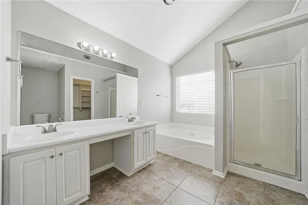a spacious bathroom with a double vanity sink a mirror and a bathtub