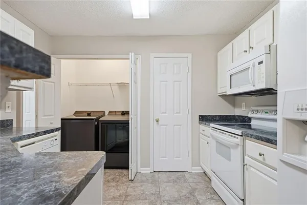 a kitchen with granite countertop white cabinets and appliances