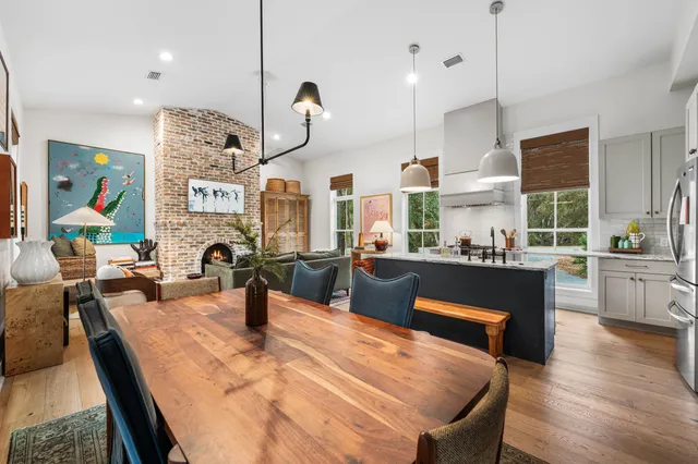 a kitchen with stainless steel appliances kitchen island granite countertop a stove a sink a dining table and chairs with wooden floor