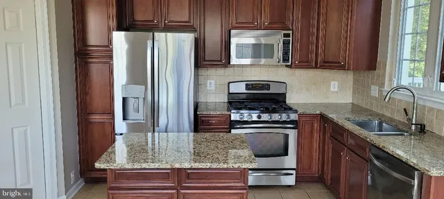 a kitchen with kitchen island granite countertop a sink stove and refrigerator