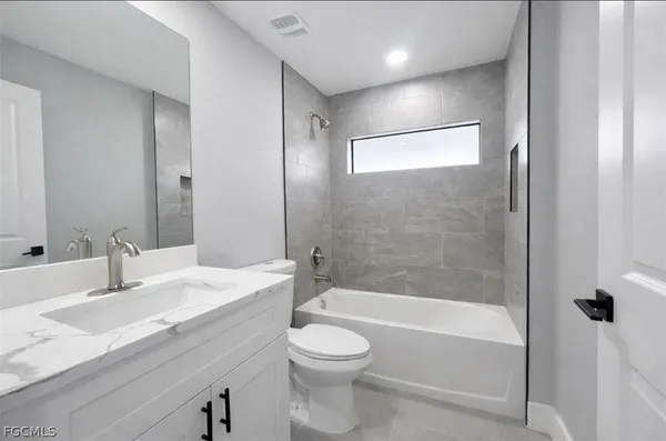 a bathroom with a granite countertop sink a toilet and shower