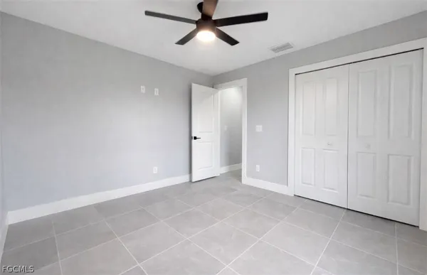 a view of an empty room and chandelier fan