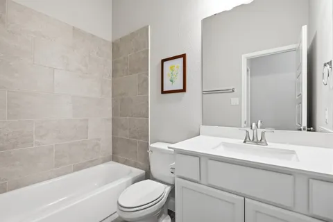a bathroom with a granite countertop sink a toilet and bathtub
