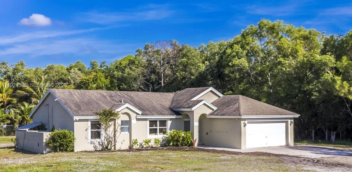 a view of a house with a big yard plants and large tree