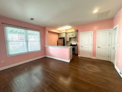 a view of an empty room with window and wooden floor