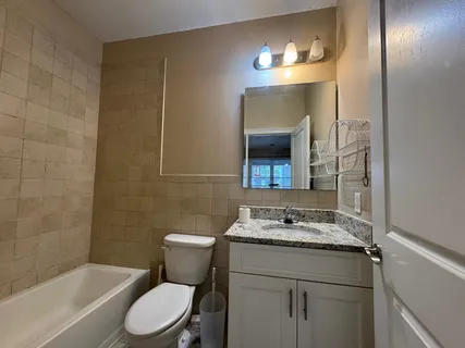 a bathroom with a granite countertop sink toilet and mirror