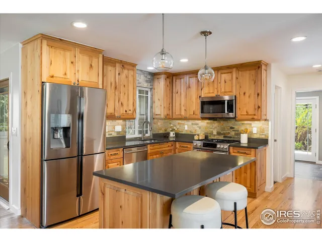 a kitchen with stainless steel appliances granite countertop a refrigerator a sink a stove and cabinets