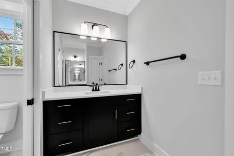 a bathroom with a double vanity sink and mirror with toilet