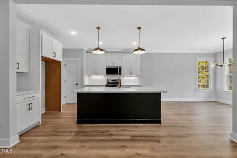 a kitchen with stainless steel appliances a stove a refrigerator and white cabinets with wooden floor