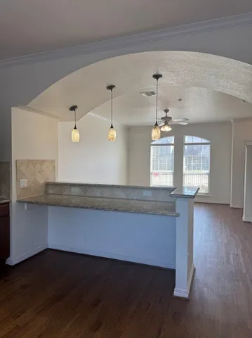 a view of a kitchen with wooden floors and a ceiling fan