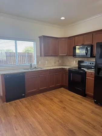 a kitchen with stainless steel appliances granite countertop a sink a stove a refrigerator with grey cabinets and wooden floor