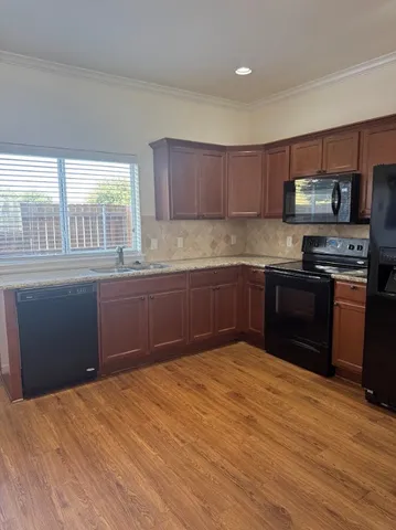 a kitchen with stainless steel appliances granite countertop a sink a stove a refrigerator cabinets and a window